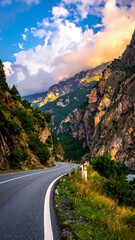 Fototapeta premium A winding road journeys through a dramatic mountain gorge, bathed in sunset light