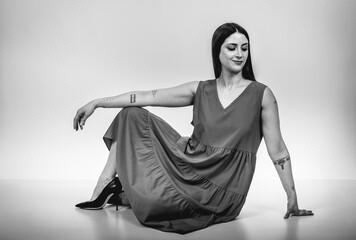 Fashion black and white portrait of a beautiful brunette woman smiling in a styling outfit on light gray studio background