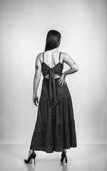 Fashion black and white portrait of a beautiful brunette woman smiling in a styling outfit on light gray studio background