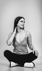 Fashion black and white portrait of a beautiful brunette woman smiling in a styling outfit on light gray studio background
