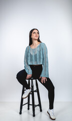 Fashion portrait of a beautiful brunette woman smiling in colorful outfit on white studio background