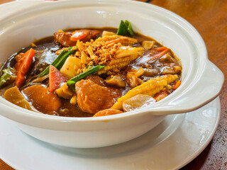 Close-up of a delicious Indonesian Cap Cai with vibrant vegetables, tofu, and rich brown sauce, topped with crispy fried shallots. Asian cuisine concept.
