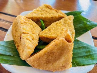 Crispy golden fried tofu triangles, a popular Indonesian snack, served with vibrant green chilies on a banana leaf. An authentic and delicious vegetarian appetizer or side.