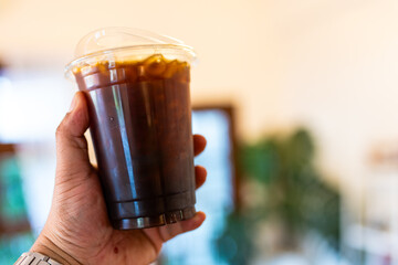 Hand holding iced black coffee or ice  americano in take away cup