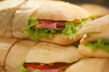 Freshly made sandwiches stacked on a counter in a busy deli