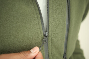 Close-up of hands zipping a green fleece jacket © Towfiqu Barbhuiya 