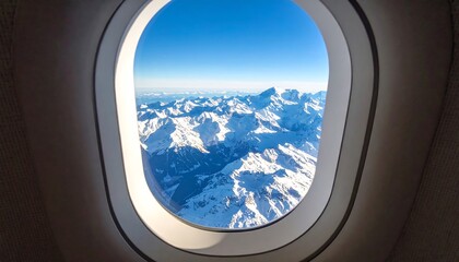 Aerial view of snow-capped mountains seen from inside an airplane window