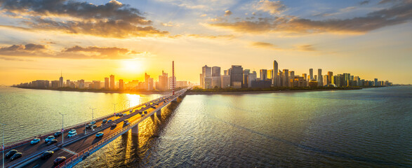 Aerial view of a long modern bridge with traffic over the river and the urban cityscape skyline at...