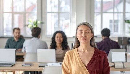 Diverse coworkers join a guided breathing exercise during a virtual meeting as laptop screens show a wellness coach with blurred background and ample top copy space for text
