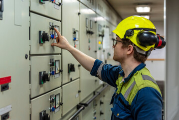 Young marine engineer during his round, checking operational parameters of engine room machineries on a merchant ship.