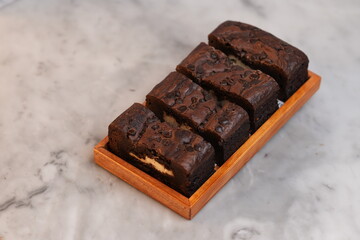 Chocolate banana loaf, sliced, on wood tray, marble backdrop