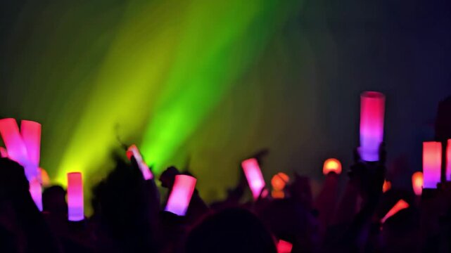 Crowd waving light sticks at concert