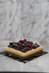 Black caramel salt cake with cherries, marble backdrop