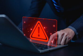 Businessman using laptop showing red warning alert symbol, representing cybersecurity threat, data protection risk, computer virus, and system security warning in digital business technology concept.
