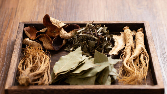 traditional Chinese herbal medicine displayed on wooden tray with dried plants, roots and leaves, natural healing, holistic health, wellness concept, apothecary style.Generated by AI