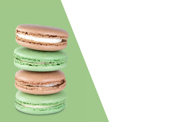 Sweet dessert composition: pastel macarons arranged in a vertical stack on a green background with copy space.