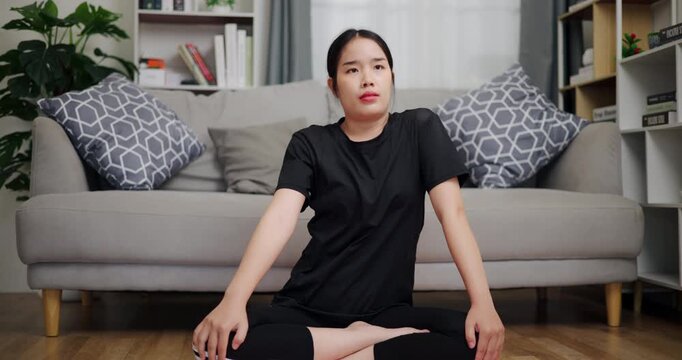 Handheld shot, Happy young woman practicing yoga with relaxation in living room at home. Leisure activity. Health care.
