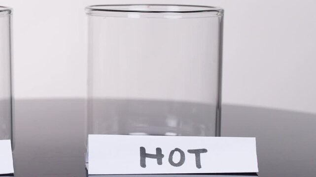 Hand Placing 'Hot' Label on Empty Glass Beaker