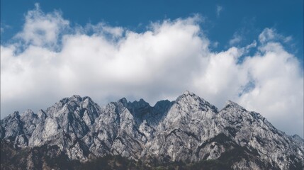 Rugged mountain range with rocky peaks and ridges under a sky filled with scattered clouds,