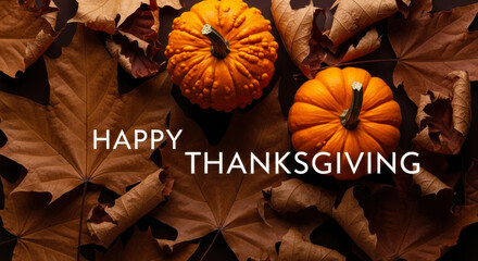 Happy thanksgiving text overlaid on a bed of dried autumn leaves with two small pumpkins