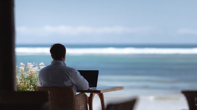 A male remote worker at a beachside cafe with his laptop, enjoying the digital nomad lifestyle.