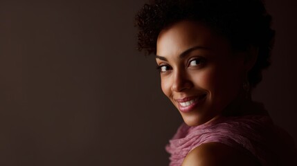 An African-American woman with natural hair smiling warmly at the camera, studio portrait with soft lighting.