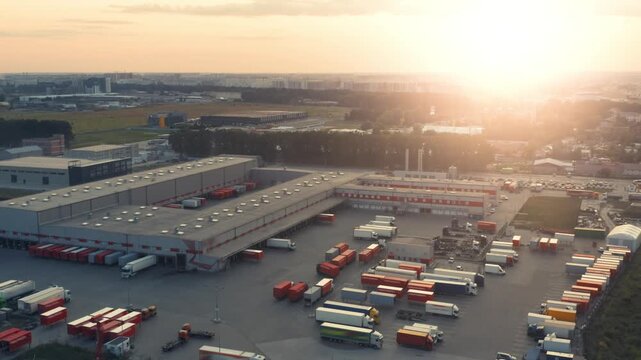 Aerial All-Round View of Modern Logistics Distribution Center at Sunset | Warehouse Complex with Semi-Trailer Trucks at Loading Docks | Commercial Freight Hub Operations
