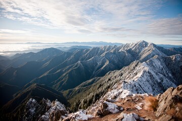 Majestic snow-covered mountains, dense forests under a bright, clear blue sky.