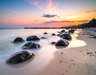 Scenic seascape at sunset with smooth water, rocks, and colorful sky