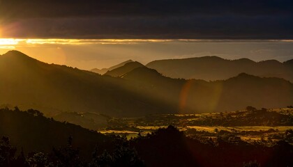 Serene sunrise over rolling hills, casting golden light on a misty valley with distant mountains