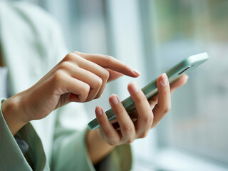 スマホを操作する女性の手元　A close-up of a woman's hands operating a smartphone　Generative AI