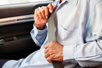 A man hand seen fastening his seat belt inside his car