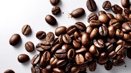 Topdown view of glossy dark roasted coffee beans scattered across a bright white surface with ample copy space on the right for design or branding