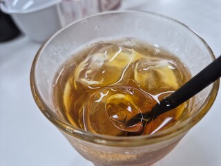 Refreshing iced tea with crystal-clear ice cubes and a straw, perfect for a hot summer day. Top view close-up