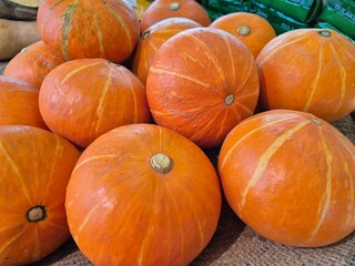 Fresh orange pumpkins neatly arranged in a market display, symbolizing harvest and healthy food