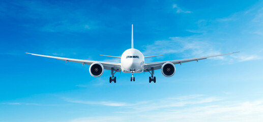 Obraz premium White airplane flying Airbus A330 front view in the blue sky background. Modern passenger jet airplane.