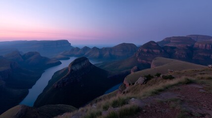 Dramatic panoramic view of the drakensberg mountains at sunset with deep blue lake and iconic three rondavels silhouetted against a glowing sky, evoking tranquility and awe