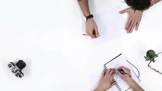 Top View Brainstorming Session: Two People Working with Notebook and Sketch

