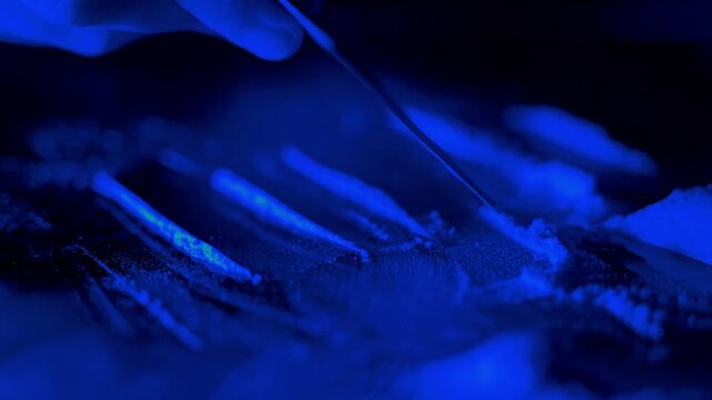 Close up macro shot of white drug powder lines prepared under blue neon light