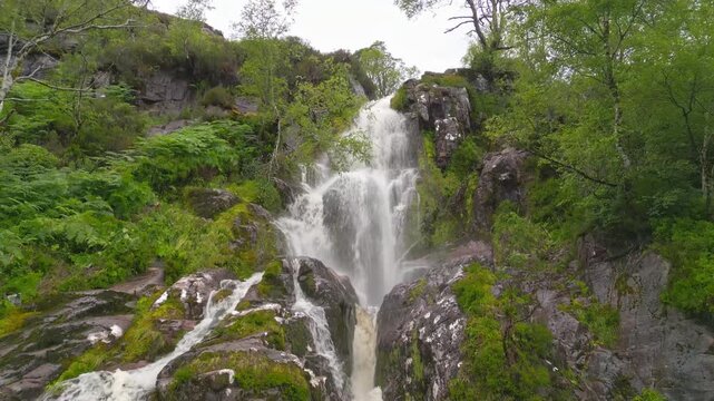 Aerial view of a strong Highland waterfall dropping through dark rocks and ferns