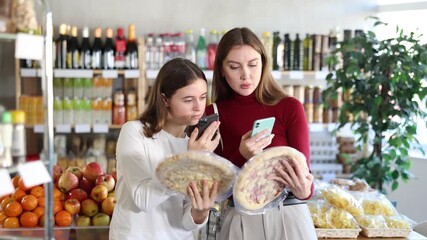 Young mother with a teenage daughter scans the QR code of a package with a pizza on phone. European family scans mobile barcode of packages in the supermarket. High quality 4k footage
