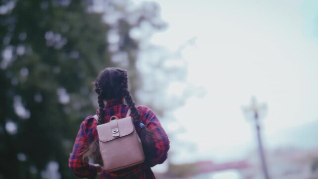 Urban Adventure: Girl with Backpack Hurrying to School Through the City on a Cloudy Day