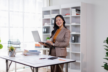 Attractive asian woman, Manager with laptop stands in office area of coworking space
