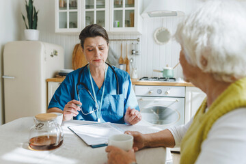 Side view of essential in-home medical support and companionship for elderly, caring nurse in blue...