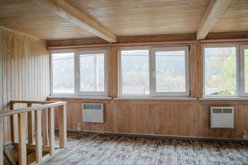 Imagine a bright and airy interior of a beautifully designed wooden room that features large, expansive windows, allowing for breathtaking scenic views of the outdoors, enhancing the overall ambiance