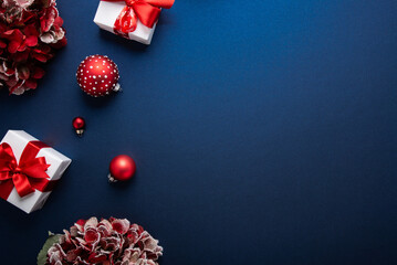 Merry Christmas and Happy Holidays greeting card, frame, banner. New Year. Red and white Christmas decorations and gifts on blue background top view. Winter xmas holiday celebration theme.