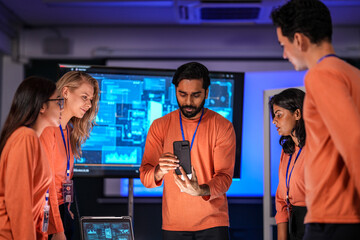 In a futuristic logistics control tower, a team manages the global supply chain, using a tablet and AI-powered dashboards to coordinate autonomous shipping and prevent disruptions.