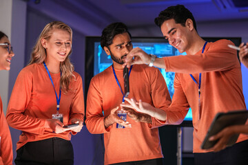 A diverse team of young innovators in a tech lab presents a new smartphone prototype,...