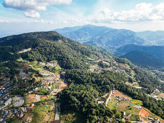 Fototapeta premium Aerial view of Mon Jam, Chiang Mai, Thailand — surrounded by mountains under a bright blue sky, with stunning natural scenery and peaceful atmosphere.