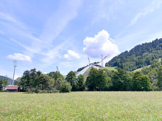 Panorama of the fenced buildings of a mountain village near a ski resort against the background of cloud patterns in the blue sky.